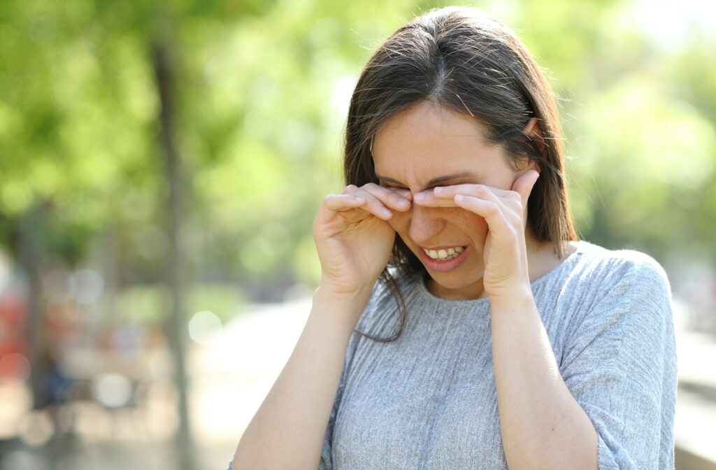 A woman wincing while rubbing her eyes due to dry eyes