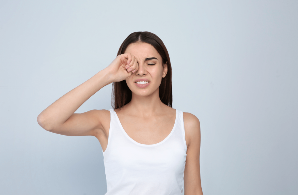 A young woman rubbing her right eye due to dry eye pain