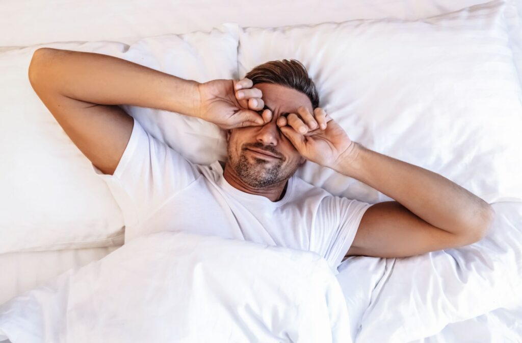 A man rubbing his eyes after waking up.